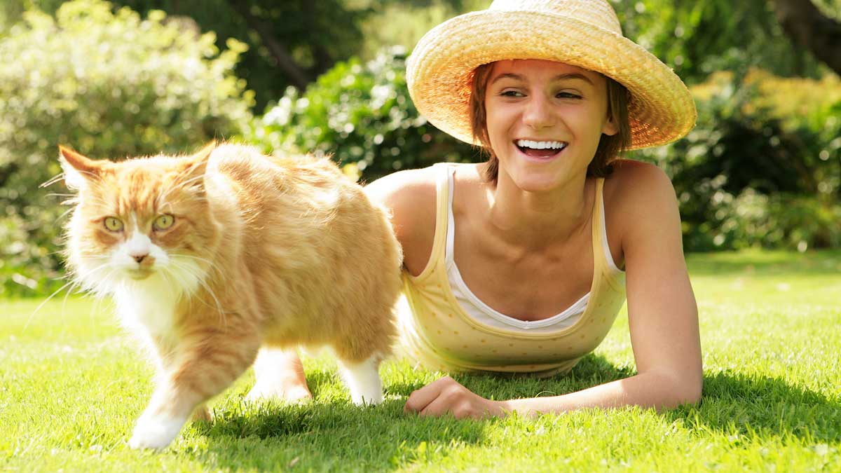 A woman playing outside with her cat.