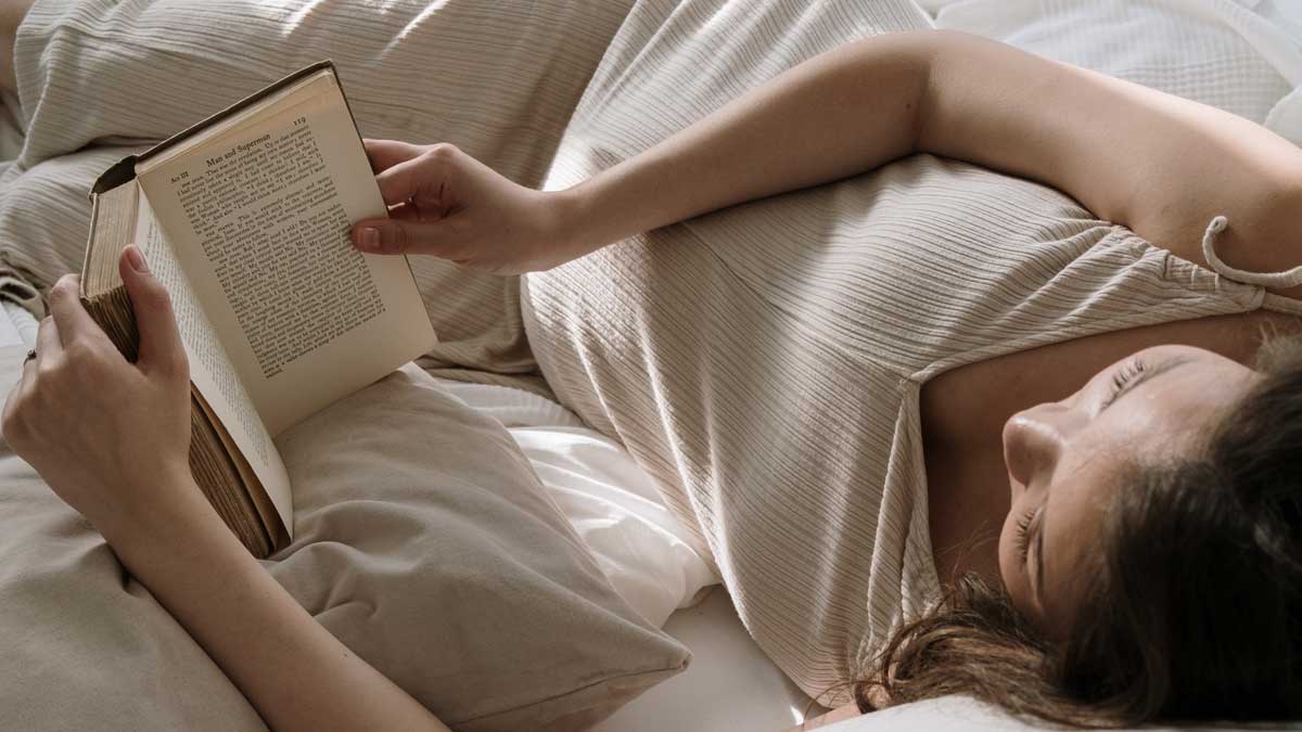 woman lying in bed reading a book