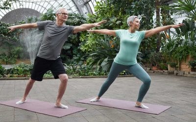 mature man and woman doing yoga surrounded by plants